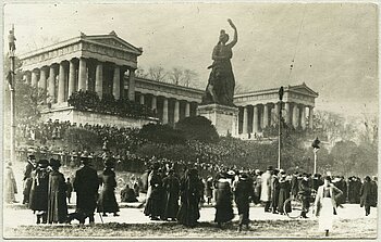 Friedenskundgebung auf der Theresienwiese in München am 7. November 1918 mit Blick auf die Statue der Bavaria und die Ruhmeshalle. Die Ruhmeshalle erinnert an berühmte Persönlichkeiten aus dem deutschen Sprachraum. Wie alle Bauten und Monumente der Ära König Ludwigs I. sollten auch Bavaria und Ruhmeshalle bayerische mit deutscher oder auch europäischer Identität verbinden.
